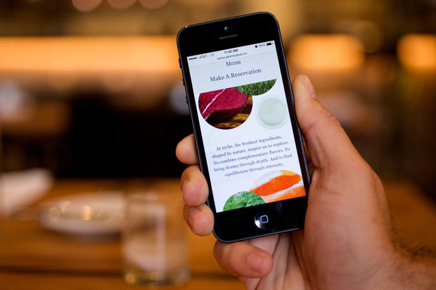 Guest holding an iPhone with Niche Restaurant mobile website