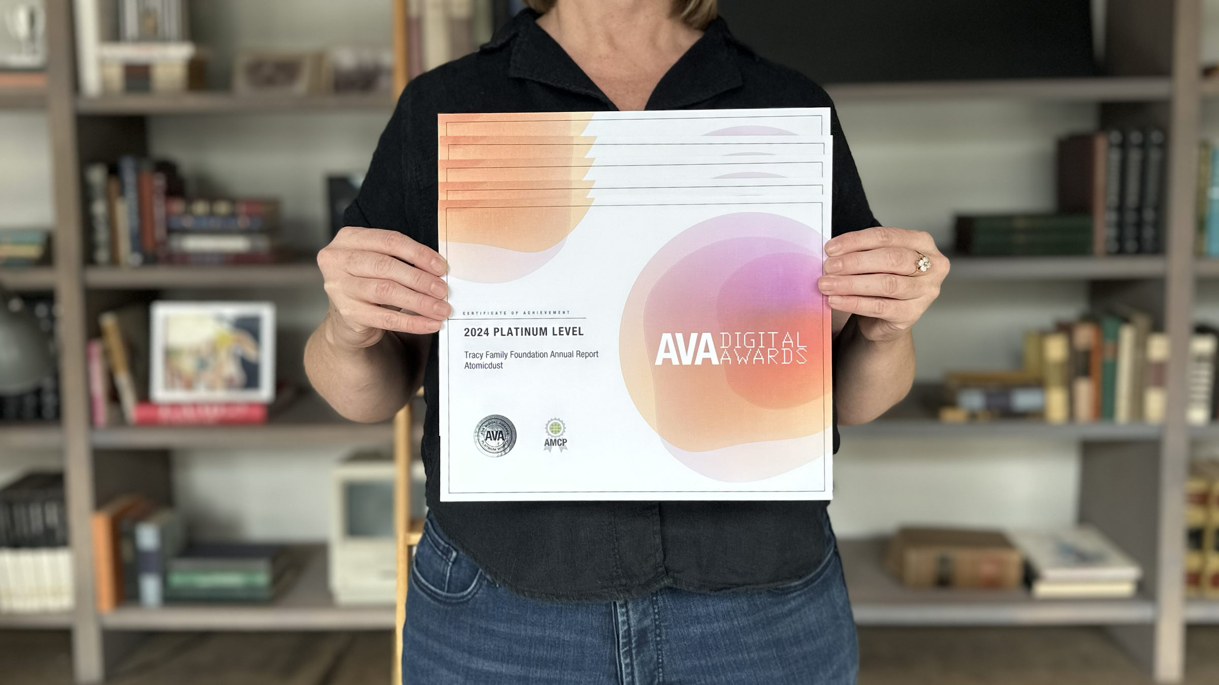 An Atomicdust team member holds the five 2024 AVA Digital Awards certificates representing winning projects