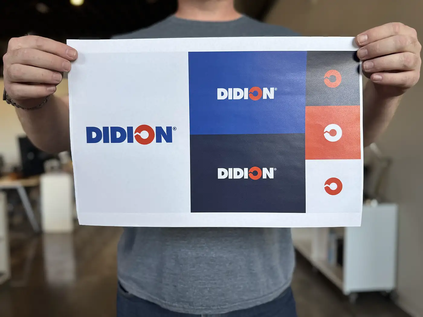 Atomicdust team member holds a print out of DIDION's refresh brand logo design