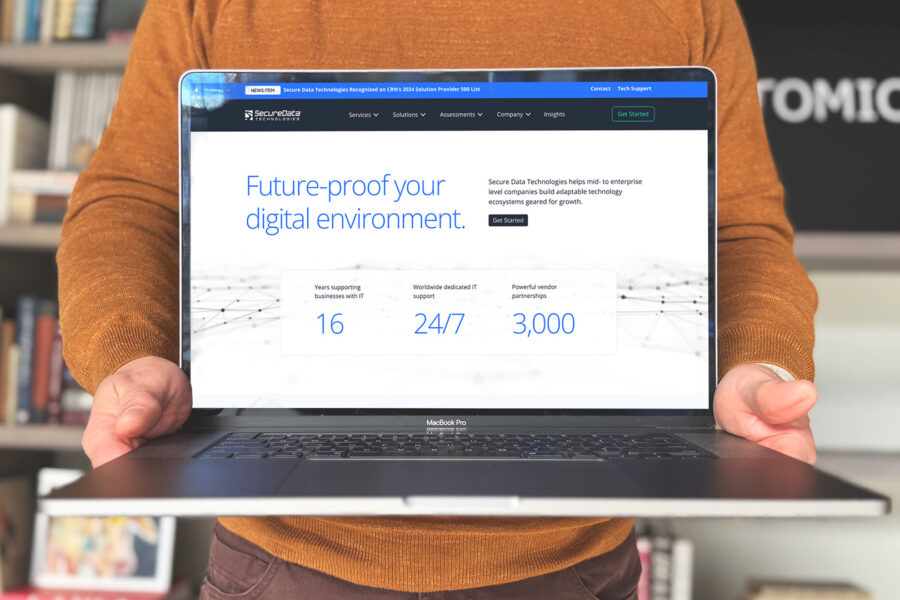 An Atomicdust team member holds a laptop with the Secure Data Technologies website