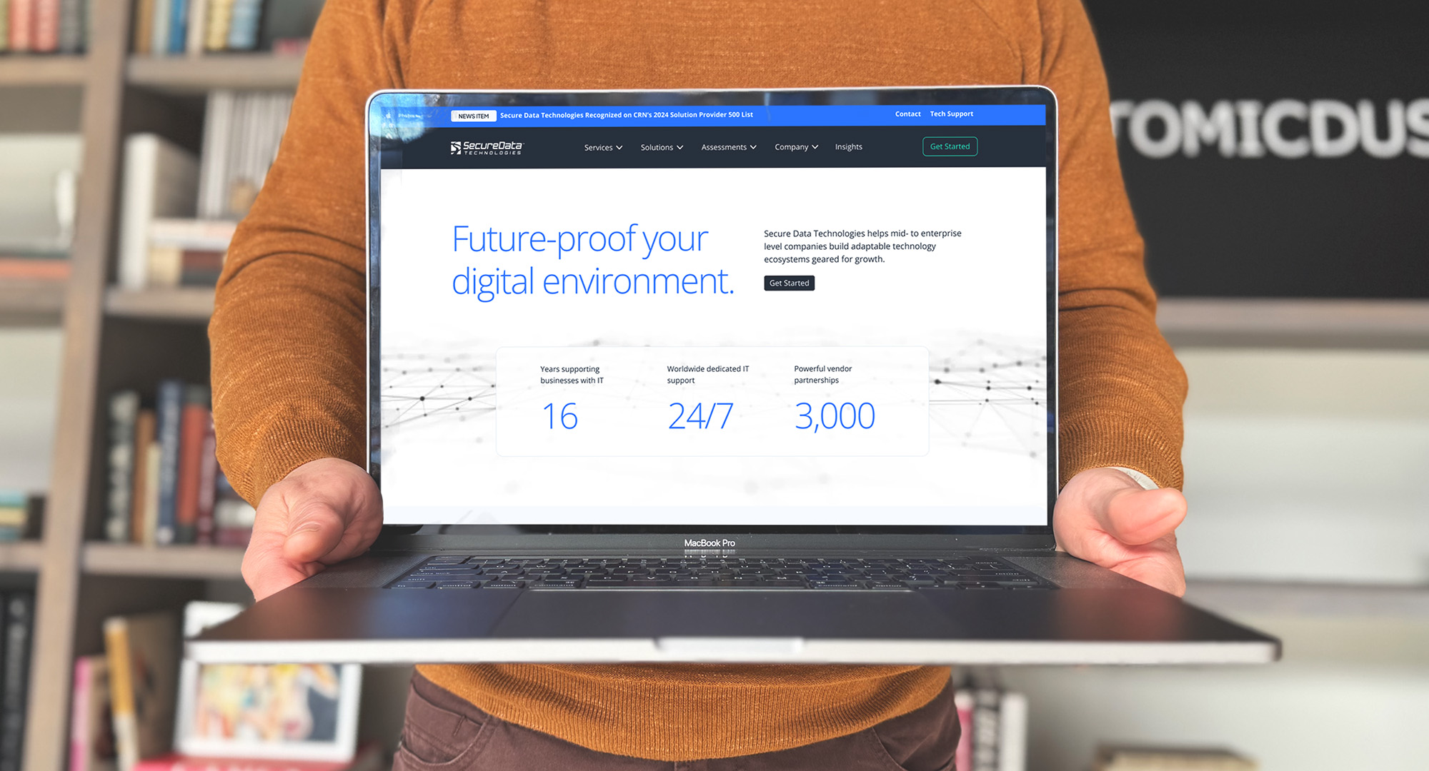 An Atomicdust team member holds a laptop with the Secure Data Technologies website